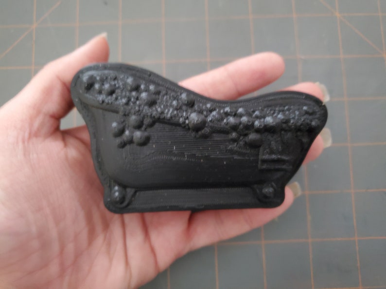 Puede incluir: Una peque&ntilde;a ba&ntilde;era negra con un dise&ntilde;o decorativo alrededor del borde. La ba&ntilde;era est&aacute; hecha de pl&aacute;stico liso y duro.