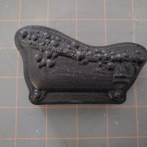 Puede incluir: Una ba&ntilde;era de pl&aacute;stico negro con un dise&ntilde;o decorativo. La ba&ntilde;era es peque&ntilde;a y parece ser una versi&oacute;n en miniatura de una ba&ntilde;era real.