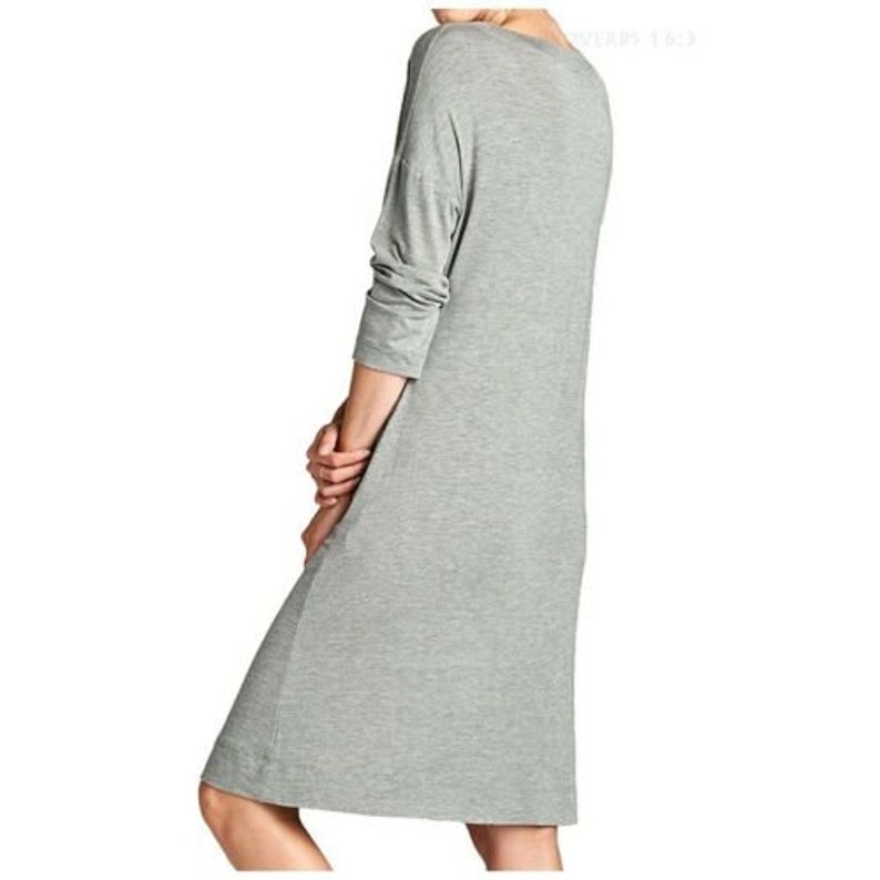 Puede incluir: Un vestido gris de manga larga con cuello de barco y corte holgado.