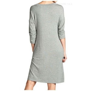 Puede incluir: Un vestido gris de manga larga con cuello redondo. El vestido est&aacute; hecho de una tela suave y el&aacute;stica y tiene un corte holgado.