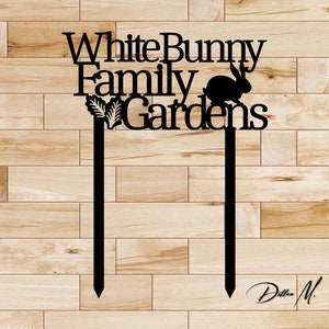 Puede incluir: Estaca de jard&iacute;n de metal negro con el texto "White Bunny Family Gardens" y una silueta de un conejo.