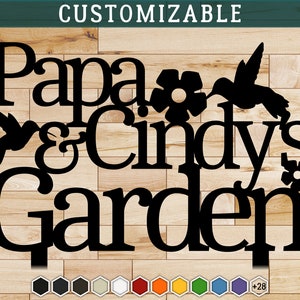 Puede incluir: Letrero de metal negro con el texto "Papa & Cindy's Garden" con dos colibr&iacute;es y flores. El letrero es personalizable con una variedad de colores.