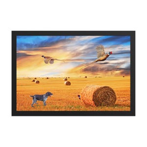 May include: A framed wall art print depicting a golden wheat field with scattered hay bales under a sunset sky. A dark gray and white spotted dog stands in the foreground, while two pheasants fly above the field and one hides near a bale.