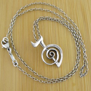May include: A silver necklace with a pendant featuring a stylized musical note with a spiral design.