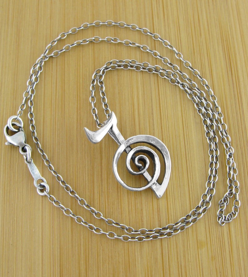 May include: A silver necklace with a pendant featuring a stylized musical note with a spiral design.