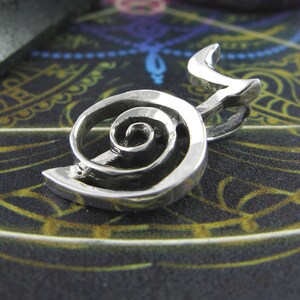 May include: A silver pendant featuring a double spiral design. The spiral is a symbol of growth, transformation, and the interconnectedness of all things.