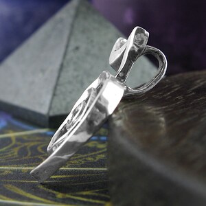 May include: A silver pendant in the shape of a heart with a textured surface.