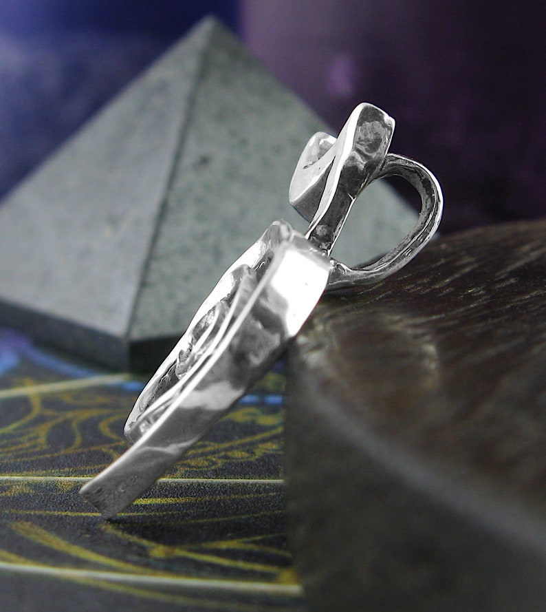 May include: A silver pendant in the shape of a heart with a textured surface.