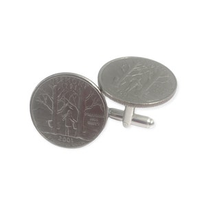 May include: A pair of silver cufflinks featuring a 2001 Vermont state quarter on each side. The quarter features a girl standing in a forest with the words "Freedom and Unity" on a sign.