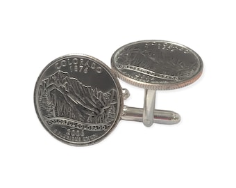 Puede incluir: Un par de gemelos de plata con una moneda de 25 centavos de Colorado de 2006 con la inscripción "Colorful Colorado" y "1876".