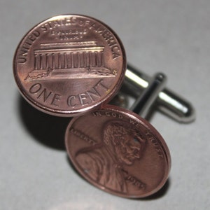 May include: A pair of cufflinks made from copper US pennies. The cufflinks feature the Lincoln Memorial on one side and the profile of Abraham Lincoln on the other. The pennies are dated 1985.