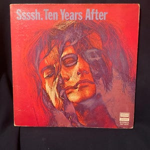 Puede incluir: Funda de álbum de vinilo vintage para "Ssssh. Ten Years After" con fondo rojo. La portada presenta una imagen multicapa de un rostro en tonos rojos y morados. El título del álbum está en texto blanco.