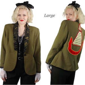 May include: Olive green blazer with a black and gold patterned collar and a decorative patch on the back. The blazer has a single button closure and is worn with black pants. The word "Large" is visible in the image.