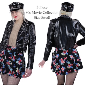 May include: A three-piece 80s movie collection costume set in size small. The set includes a black faux leather jacket with silver studs, a black skirt with a floral print, and a black vinyl cap.
