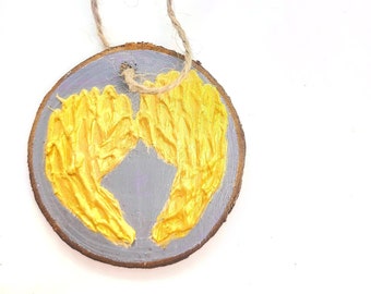 WOOD WINGS ORNAMENT - 2.5" Christmas Ornament on a Wood Tree Slice with Gold Wings on a Gray Background