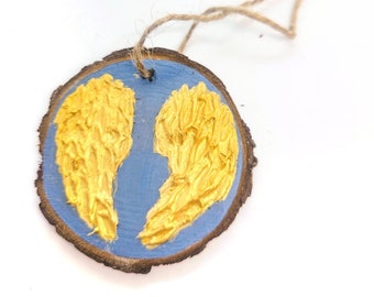 WOOD WINGS ORNAMENT - 2.5" Christmas Ornament on a Wood Tree Slice with Gold Wings on a Blue Background