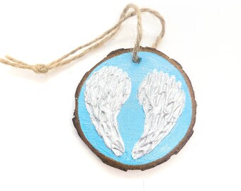 WOOD WINGS ORNAMENT - 2.5" Christmas Ornament on a Wood Tree Slice with White and Silver Wings on a Turquoise Blue Background