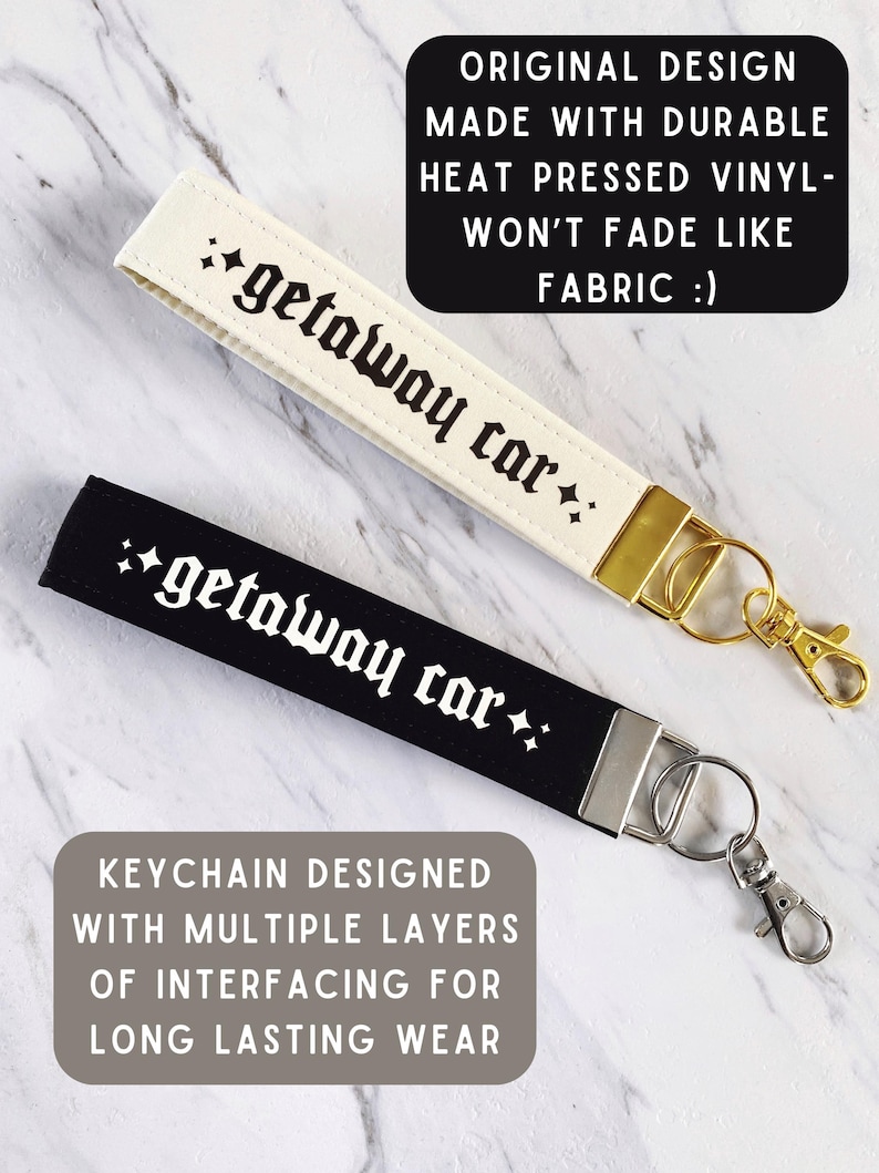 May include: Two keychains, one cream and one black, each with the text "getaway car" in a gothic font. The cream keychain has a gold clasp, while the black one has a silver clasp. Text on the image states "Original design made with durable heat pressed vinyl - won't fade like fabric".