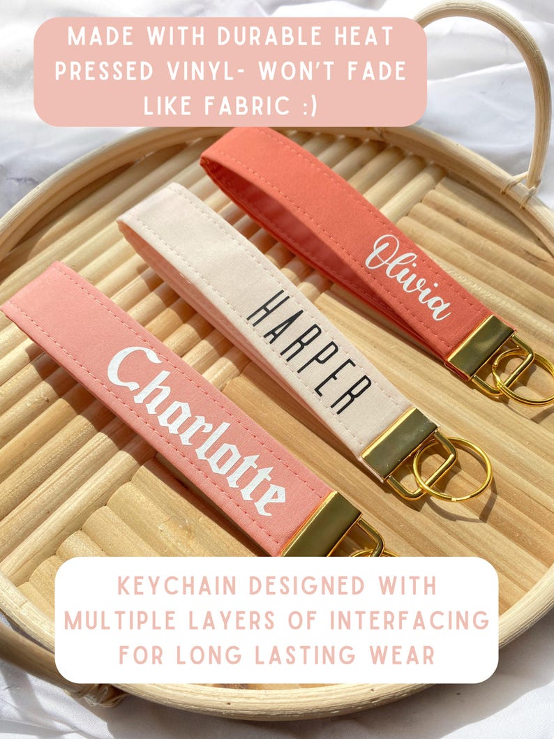 May include: Three personalized keychains in coral, cream, and pink, each with a gold-tone metal accent and a keyring. The keychains are labeled with the names "Charlotte", "Harper", and "Olivia" in white script. The text in the image says "Made with durable heat pressed vinyl" and "Keychain designed with multiple layers of interfacing".