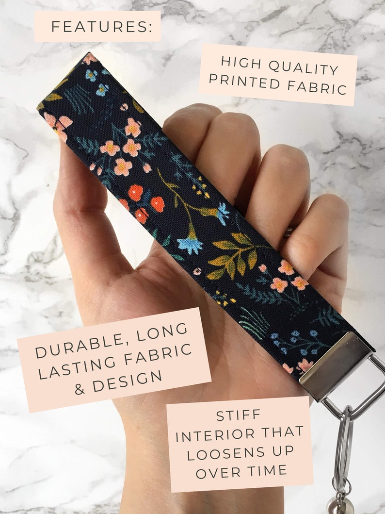 May include: A floral patterned wristlet key fob with a dark background and colorful flowers. The key fob has a metal clasp and key ring. The text on the image says "High Quality Printed Fabric" and "Durable, Long Lasting Fabric & Design."