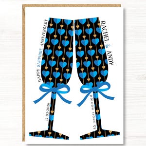 May include: A greeting card featuring two champagne flutes with blue heart patterns on a black background. The card reads "Happy Sapphire Anniversary" and "Rachel & Andy", with the date "12-03-2026" and "45 years married".