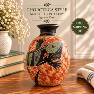 May include: A round ceramic vase featuring a sgraffito design of an iguana with green and black details against a mottled reddish-brown background. The vase has a dark, narrow neck with thin horizontal lines and a wide, rounded body.