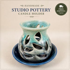 May include: A handmade studio pottery candle holder with a teal and blue glaze, featuring a cut-out leaf pattern. The piece consists of a rounded, hollow vessel resting on a matching circular saucer, displaying a glossy finish and organic shapes.