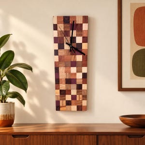 May include: A rectangular wall clock featuring a mosaic pattern of small, square wooden tiles in various shades of brown, tan, and deep purple. The clock has a simple black hour hand and a black minute hand centered on the wooden surface.