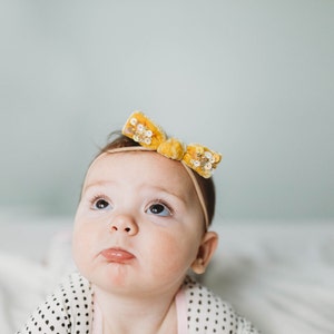 Baby with a knot size bow headband on its head.