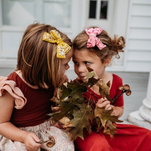 Photo of two little girls with doodlelidoo bows in pink and yellow in their hair.