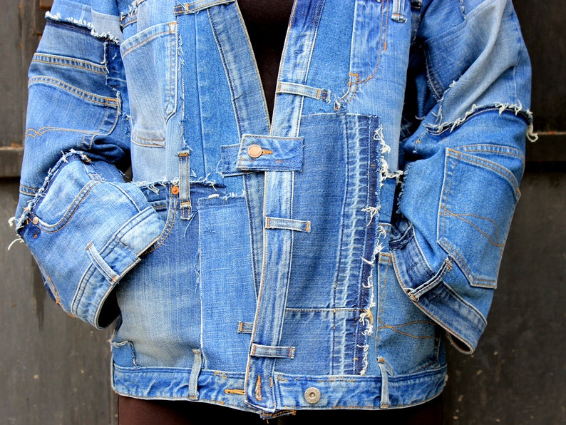 May include: A blue denim jacket made from multiple pieces of denim sewn together. The jacket has a frayed and distressed look, with visible stitching and seams.