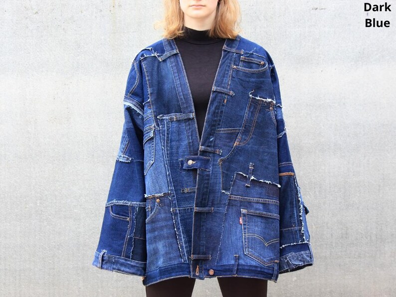 May include: A dark blue denim jacket made from patchwork pieces of denim. The jacket has a long, loose fit and a collarless design.