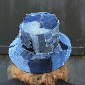 Könnte beinhalten: Ein blauer Jeans-Bucket-Hut aus Patchwork-Jeansstoff. Der Hut hat eine breite Krempe und ist aus verschiedenen Blautönen von Jeansstoff gefertigt.