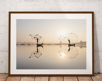 May include: Two fishermen in boats cast their nets in a still lake at sunrise. The nets create a circular pattern in the water, reflecting the golden light of the sun.