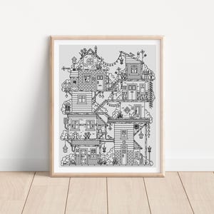 Peut inclure: Impression en noir et blanc d'un village fantaisiste de maisons empilées, chacune avec des détails architecturaux uniques. L'œuvre est encadrée dans un cadre en bois clair et repose sur une surface en bois.