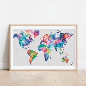 Peut inclure: Une carte du monde brodée au point de croix, encadrée, avec un effet aquarelle. La carte est brodée dans des tons de bleu, vert, violet, rose et jaune.