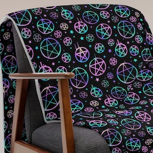 May include: A black throw blanket with a repeating pattern of iridescent pentagrams and stars. The blanket is draped over a wooden armchair.