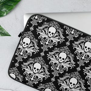 May include: Black laptop sleeve with a white skull and damask pattern.