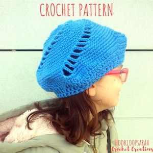 May include: A blue crochet beanie with a unique open stitch pattern. The beanie is worn by a person with brown hair and pink glasses. The text "HOOKLOOPSARAH Crochet Creations" is visible in the bottom right corner of the image.