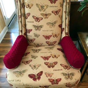 May include: A red and cream armchair with a butterfly pattern and the words "Monarch", "Painted Lady", and "Chalk Blue" printed on the fabric. The chair has red armrests and gold trim.