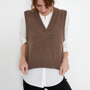 May include: A brown knitted sleeveless vest with a V-neck.
