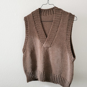 May include: A brown knitted sleeveless vest with a V-neck.