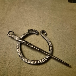 May include: A white ceramic mug with a black handle and the text "But First, Coffee" in a bold, black font. The mug is sitting on a wooden surface. The mug is approximately 4 inches tall.