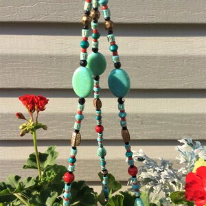 May include: Three strands of beaded macrame plant hanger with turquoise and red beads, gold accents, and turquoise teardrop-shaped beads at the bottom.