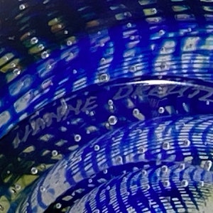 K&ouml;nnte beinhalten: Ein blauer Glas-Briefbeschwerer mit einem wirbelnden Muster und Luftblasen. Der Briefbeschwerer ist signiert mit "Limoine" und "Dreizler".