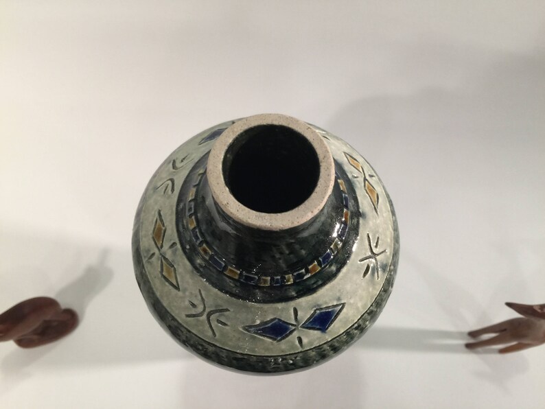 Może przedstawiać: Ceramiczny wazon z geometrycznym wzorem w kolorze niebieskim, białym i złotym. Wazon ma szeroki otw&oacute;r i wąską szyjkę.