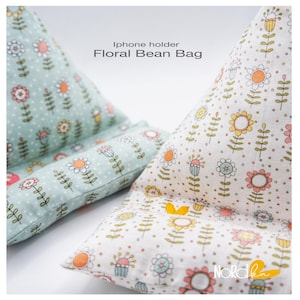 May include: Two floral bean bag iPhone holders. One is light green with white polka dots and colorful flower designs. The other is white with colorful flower designs. The text "iPhone holder Floral Bean Bag" is visible.