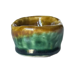 May include: A small, green and brown ceramic bowl with a slightly uneven rim. The bowl has a glossy finish and is perfect for serving small snacks or condiments.