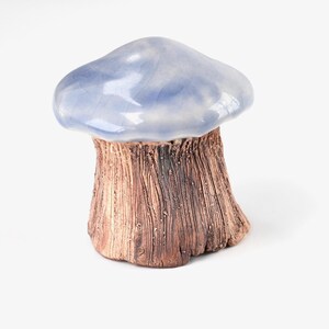 May include: A ceramic mushroom sculpture with a light blue glazed top and a brown textured base.