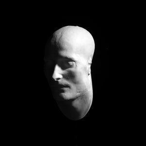 May include: A white plaster cast of a person's head and face. The cast is of a man's face, and the features are visible, including the nose, eyes, and mouth.